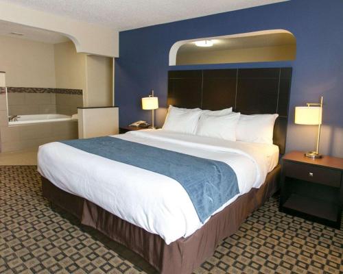 a hotel room with a large bed and a bath tub at Comfort Suites Benton Harbor - St Joseph in Benton Harbor