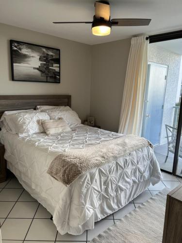 a bedroom with a white bed with a ceiling fan at Gulf Shores Surf and Racquet Club Unit 406C in Gulf Shores