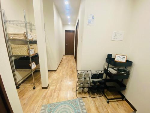 ein Flur mit einem Zimmer mit Holzboden und einem Regal in der Unterkunft 時間を忘れる貸別荘オールブルー in Hiroshima