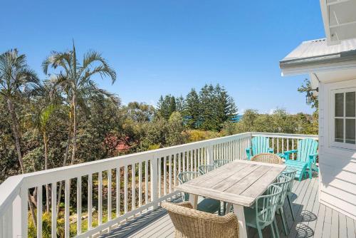 a wooden table and chairs on a balcony with palm trees at Salt Spray - Full House in Dunbogan
