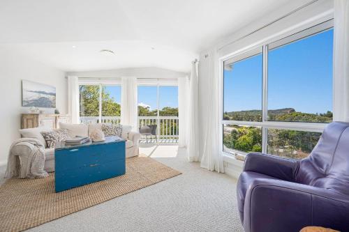 a living room with a purple couch and a large window at Salt Spray - Full House in Dunbogan