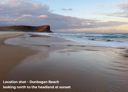 a beach with a rock in the ocean at Salt Spray - Full House in Dunbogan