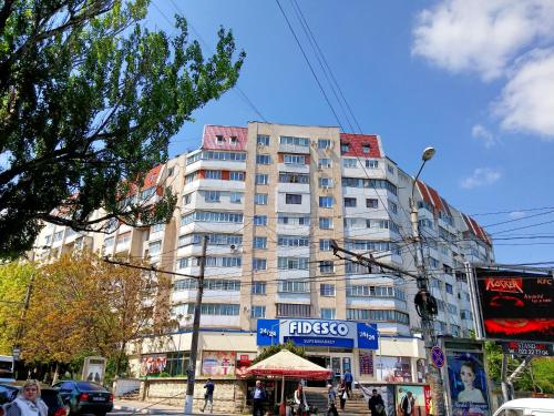 wysoki budynek na ulicy miejskiej z ludźmi przed nim w obiekcie Apartment in City Center, street Banulescu Bodoni 57 w Kiszyniowie