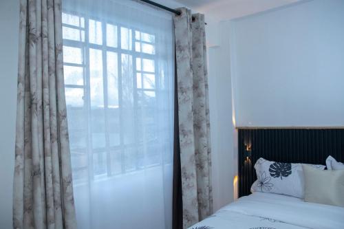 a bedroom with a bed and a large window at The Escape Nanyuki in Nanyuki