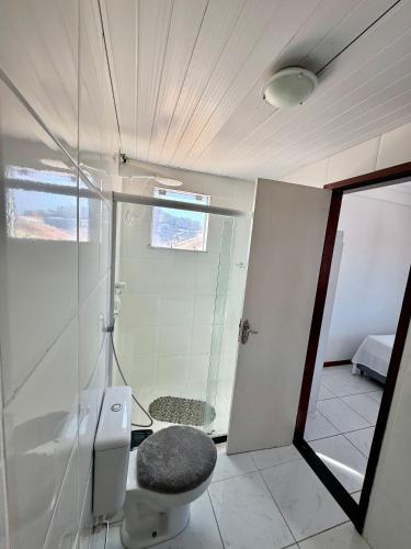 a bathroom with a toilet and a glass shower at Hospedatom - Apartamento Beira-Mar Praia Grande Arraial do Cabo in Arraial do Cabo