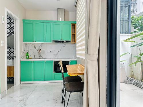 a kitchen with green cabinets and a table at ANVI HOUSE - Vinhomes Marina Hải Phòng in Xóm Niêm