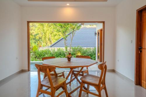 a dining room with a table and chairs and a large window at Arca Jungle View Luxury Villa Ubud in Ubud