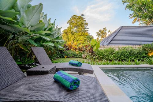 a patio with a swimming pool and two towels at Arca Jungle View Luxury Villa Ubud in Ubud