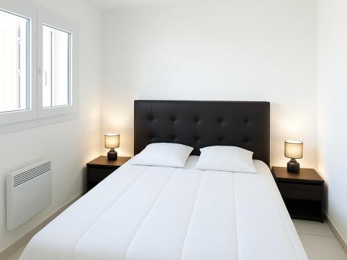 une chambre avec un grand lit blanc avec deux lampes dans l'établissement Charmant T2 climatisé rénové, proche plage et commerces à Argelès-sur-Mer, avec balcon et parking privé - FR-1-732-68, à Argelès-sur-Mer