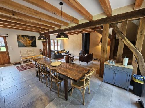 Il dispose d'une cuisine et d'un salon avec une table et des chaises en bois. dans l'établissement Charmant gîte champêtre avec bain nordique et terrasse privative - FR-1-491-441, à Fresnes