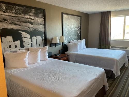 a hotel room with two beds with white sheets at Super 8 by Wyndham Colorado Springs Airport in Colorado Springs