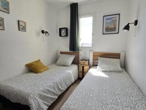 deux lits jumeaux dans une chambre avec fenêtre dans l'établissement Appartement Bord de Mer avec Parking et Piscine - Confort et Commodité - FR-1-801-4, au Cap d'Agde