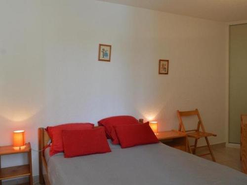 une chambre avec un lit avec deux oreillers rouges dans l'établissement Appartement calme au Cap d'Agde pour 5 personnes, proche plage - FR-1-749-100, au Cap d'Agde