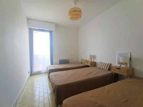 une chambre avec trois lits et une fenêtre dans l'établissement Canet-en-Roussillon - T3 lumineux 6 pers avec grande terrasse face mer - FR-1-794-97, à Canet