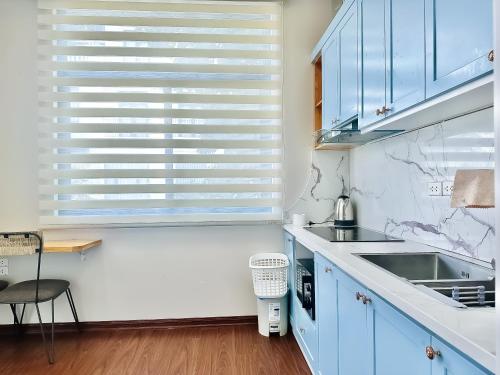 a kitchen with blue cabinets and a window at ANVI HOUSE - Vinhomes Marina Hải Phòng in Xóm Niêm