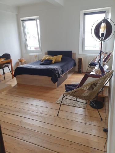 - une chambre avec un lit, une chaise et deux fenêtres dans l'établissement STUDIO ENTRE MER et FORET, à Campagne-lès-Hesdin