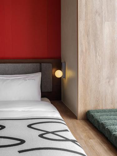 a bedroom with a bed and a red wall at NOA HOTEL BEIJING LONGFU-The Forbidden City in Beijing