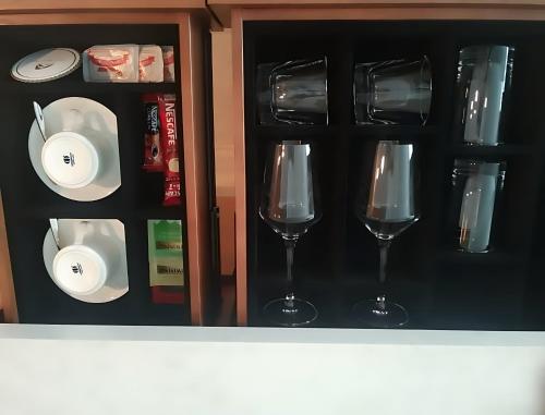 three wine glasses and plates in a cabinet at Hotel Anda China Malabo in Malabo