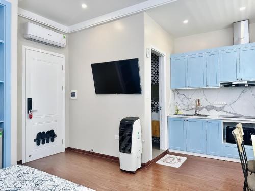 a kitchen with blue cabinets and a flat screen tv at ANVI HOUSE - Vinhomes Marina Hải Phòng in Xóm Niêm