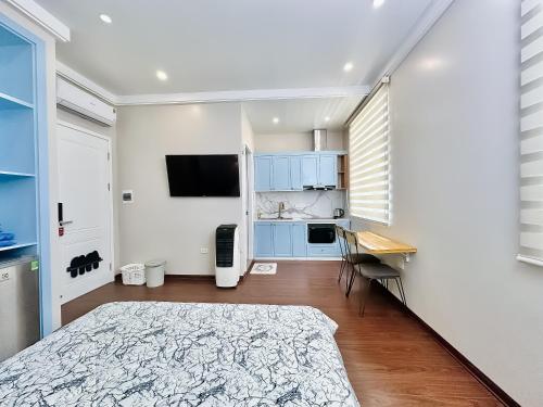 a bedroom with a bed and a desk and a kitchen at ANVI HOUSE - Vinhomes Marina Hải Phòng in Xóm Niêm