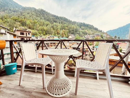 a table and chairs on a balcony with a view at The Hamlet Stay in Manāli