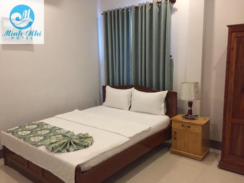 a bedroom with a bed and a table with a lamp at Minh Nhi Hotel in Tân Tạo