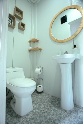 a bathroom with a white toilet and a mirror at Eco Suites El Zonte in La Libertad