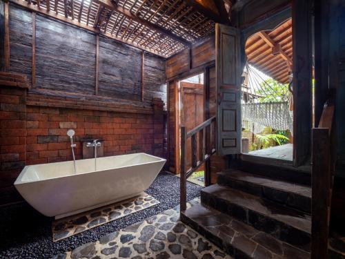 a bath tub in a bathroom with a brick wall at Aruna Jayanti Villa in Tejakula