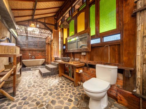 a bathroom with a toilet and a bath tub at Aruna Jayanti Villa in Tejakula
