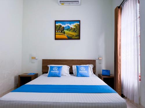 a bedroom with a large bed with blue pillows at Adiputra Guesthouse 2 by HomiQ in Ngabean