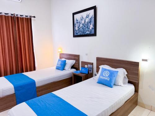 a hotel room with two beds and a window at Adiputra Guesthouse 2 by HomiQ in Ngabean