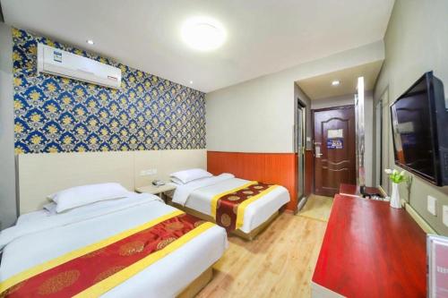 a hotel room with two beds and a flat screen tv at Kunlun Leju Business Hotel Kaifeng Gulou in Kaifeng