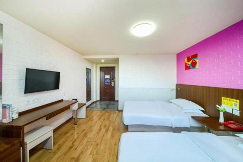 a hotel room with two beds and a flat screen tv at Kunlun Leju Business Hotel Kaifeng Gulou in Kaifeng