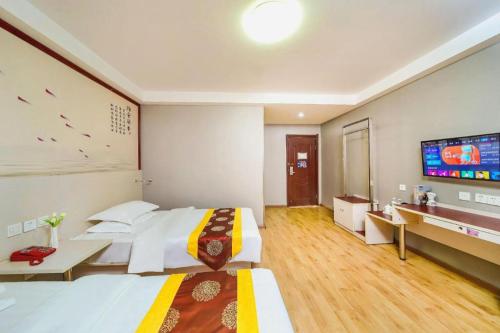 a hotel room with a large bed and a flat screen tv at Kunlun Leju Business Hotel Kaifeng Gulou in Kaifeng