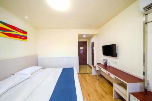 a room with a bed and a tv on a wall at Kunlun Leju Business Hotel Kaifeng Gulou in Kaifeng