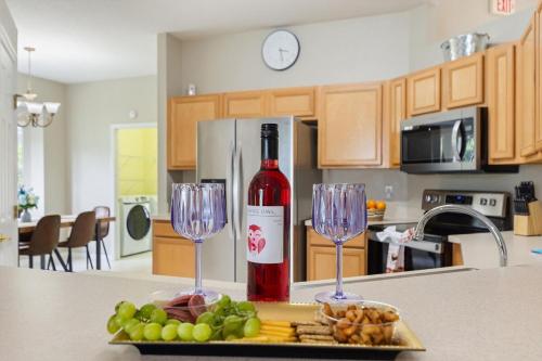 a bottle of wine and two wine glasses on a counter at Chic 4BR,Heated Pool,Jacuzzi & Dining Oasis near Disney & Legoland in Haines City