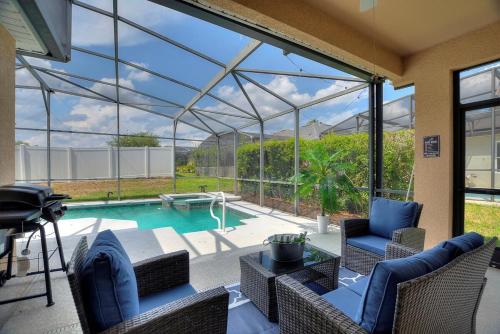 a conservatory with a pool with chairs and a table at Chic 4BR,Heated Pool,Jacuzzi & Dining Oasis near Disney & Legoland in Haines City