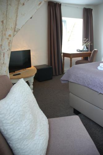 a hotel room with a bed and a desk with a television at Klooster Nieuwkerk Goirle in Goirle