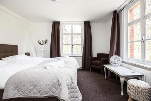 1 dormitorio con 1 cama, 1 silla y ventanas en Klooster Nieuwkerk Goirle en Goirle