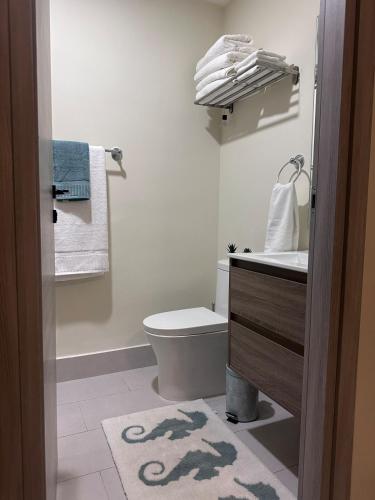 a bathroom with a toilet and a sink and towels at Vista Cana punta cana beach Paradise Pool & Lake golf Condo in Punta Cana