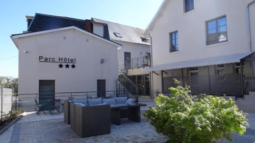 a patio in front of a building with a couch at Parc Hôtel Pompadour in Arnac-Pompadour