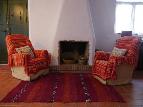 two chairs in a living room with a fireplace at El molino del abuelo in Montecorto