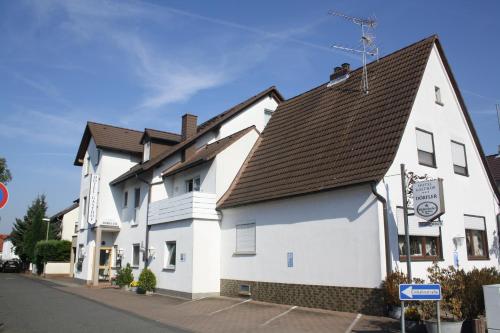 a white building with a brown roof on a street at Hotel-Dörfler Garni in Kahl am Main