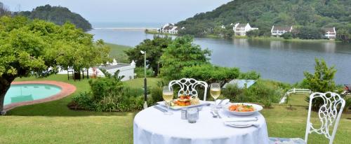 a table with a plate of food on it with a view of a lake at The Estuary Hotel & Spa in Port Edward