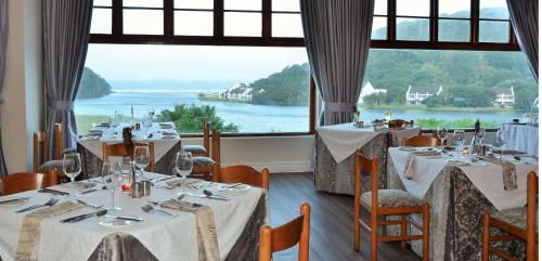 a dining room with tables with white tablecloths and a large window at The Estuary Hotel & Spa in Port Edward