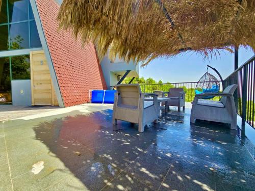 a patio with chairs and a table and a straw umbrella at Orion, Hills of Zaarour in Zaarour