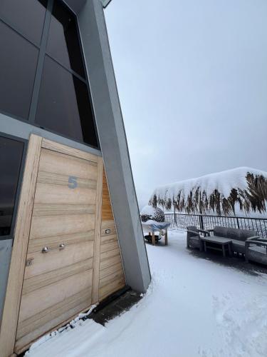 a house with a wooden door in the snow at Orion, Hills of Zaarour in Zaarour