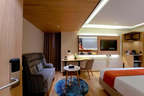 a hotel room with a bed and a chair and a desk at TGI Oberon in Bengaluru