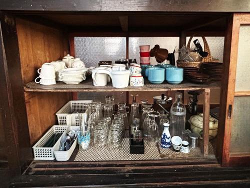 a cabinet filled with lots of dishes and utensils at 古民家一棟貸しナノビレッジ岡山 in Kaga