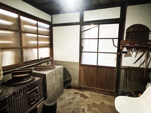 an old kitchen with a stove and a window at 古民家一棟貸しナノビレッジ岡山 in Kaga
